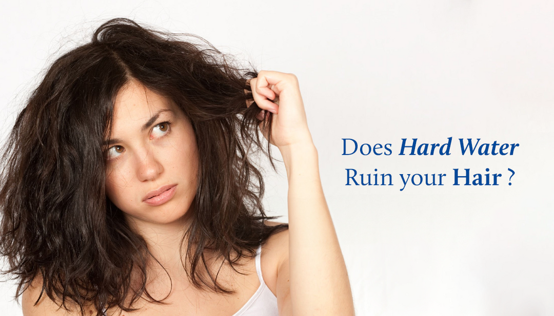 A woman grips her frizzy, dry hair with one hand while glaring upward with frustration.