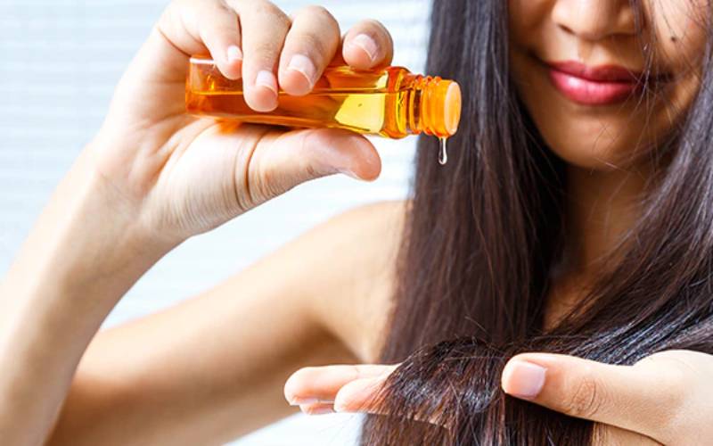 Girl is applying sesame oil on her hair